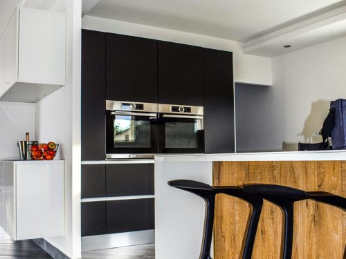 A contemporary kitchen featuring sleek cabinetry and elegant bar stools in a minimalist design.